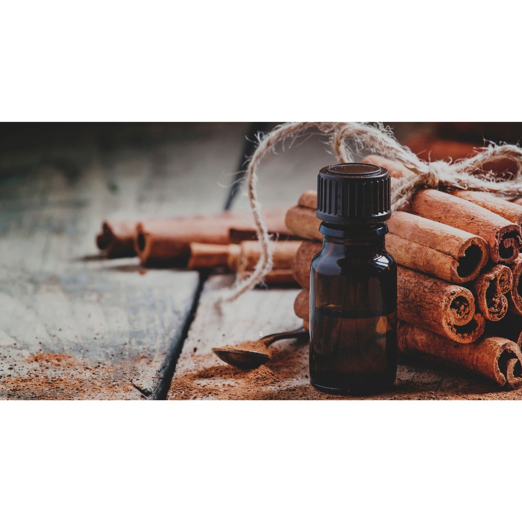 A brown essential oil bottle next to a stack of cinnamon oil